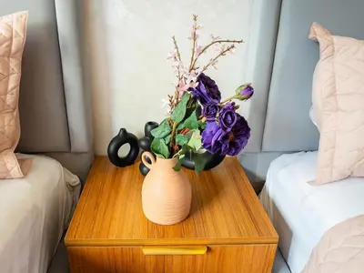 a vase with flowers on a table next to two beds at Bel appartement, piscine intérieure et extérieure in Temara