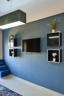 a room with a blue wall with a tv and a blue couch at Joli studio disponible sur maarif boulevard danfa in Casablanca
