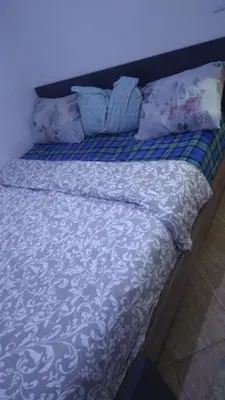 a bed with a blue and white comforter and pillows at Belle chambre sidi maarouf in Casablanca