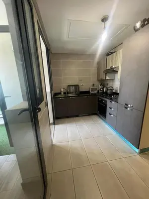 a large kitchen with black cabinets and a tile floor at Appartement convivial in Rabat