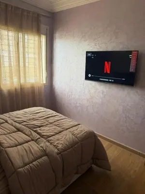 a bedroom with a tv hanging on the wall at Cozy Sunny Apartment Near Beach nd Local Amenities in Dar Ben Abdallah Ben Dehbi