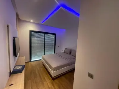 a bedroom with a bed and a window with blue lights at Prestigia appartement in Rabat