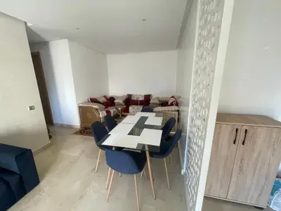 a dining room with a table and blue chairs at Prestigia appartement in Rabat
