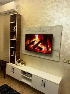 a fireplace in a living room with a tv on the wall at Cozy Apt Near Train Station in Rabat