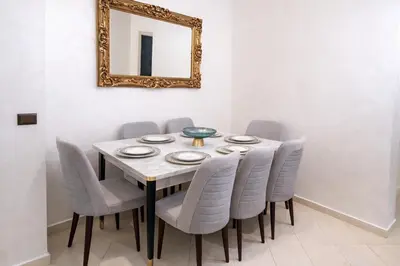 a dining room table with gray chairs and a mirror at Spacious Family-Friendly Apartment in Temara