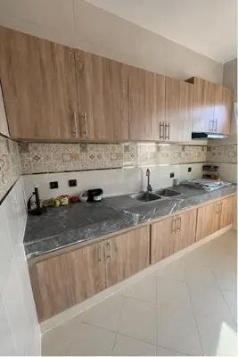 a kitchen with a sink and wooden cabinets at Spacious Family-Friendly Apartment in Temara