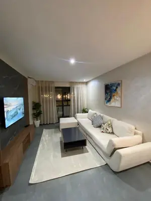 a living room with a white couch and a tv at Residence Carlton House2 STUDIOS in Roches Noires