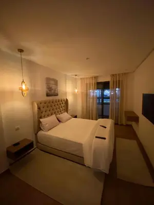 a bedroom with a white bed and a television at Residence Carlton House2 STUDIOS in Roches Noires