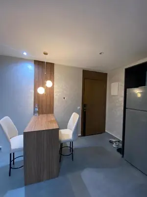 a kitchen with white chairs and a table and a refrigerator at Residence Carlton House2 STUDIOS in Roches Noires