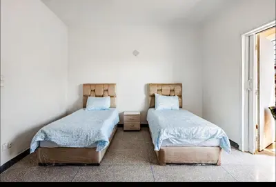 two beds in a room with white walls at Villa à harhora in Temara