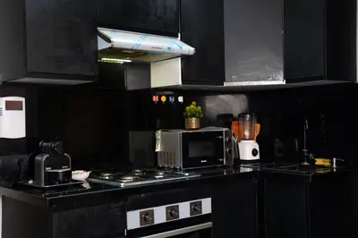 a kitchen with black cabinets and a stove with a microwave at Evasion chic et central au coeur de Maarif in Casablanca