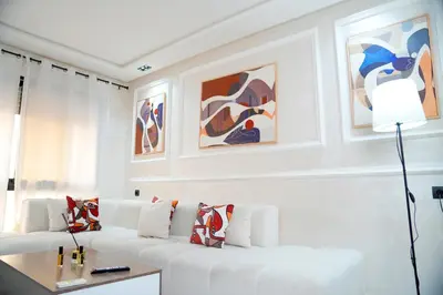 a white living room with a white couch and paintings at Evasion chic et central au coeur de Maarif in Casablanca