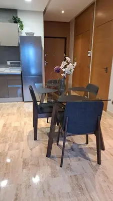 a dining room table with chairs and a vase of flowers at Luxury Appart Finance City in Casablanca