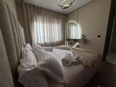 a bedroom with a bed with white sheets and pillows at Premium Studio Oasis Secure Parking High Speed Fiber Wifi Luxoria Oasis Residence Near CFC & 70p Smart TV in Casablanca