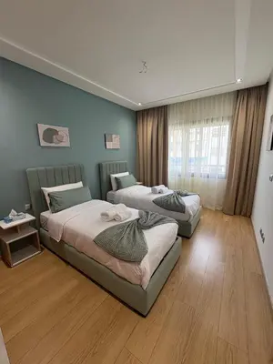two beds in a room with blue walls and wooden floors at Premium 2 Bedroom Suite Maarif Central & High-Speed Wi-Fi Fully Equipped Walk to Twin Center & Shops Next to Carrefour Val Fleuri Family-Friendly in Casablanca