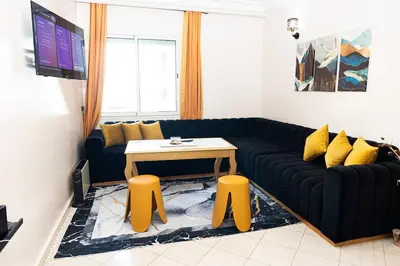a living room with a black couch and yellow stools at Apartement complets pres Ocean port de Casablanca in Casablanca