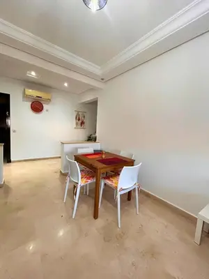 a dining room with a wooden table and white chairs at Charming apartment near Mohammedia station in Mohammedia