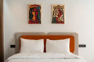 two paintings above a bed with three pillows at Résidence Happy Living in Casablanca