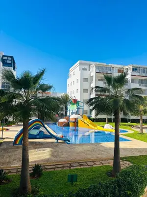 a water park with a slide and palm trees at Appartement la siesta beach resort in Mohammedia