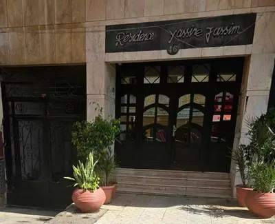a store front with two large black doors and potted plants at Corniche in Casablanca
