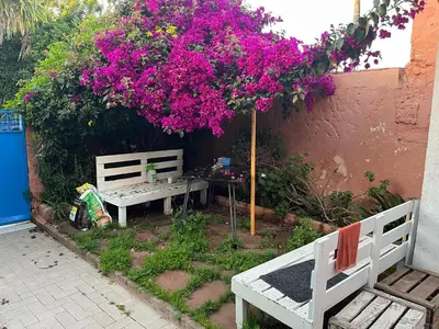 a picnic table and bench under a tree with pink flowers at Villa Cosy aux Sablettes, plage à deux pas in Mohammedia