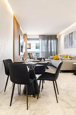 a living room with a table and chairs and a couch at Appartement de luxe sur la Corniche in Casablanca