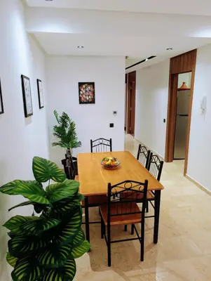 a dining room with a table and chairs and a plant at Pool view apartment, beach access, nature & quiet in Mansouria
