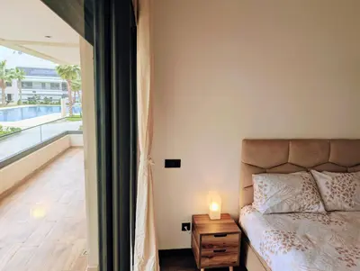 a bedroom with a bed and a candle on a night stand at Pool view apartment, beach access, nature & quiet in Mansouria
