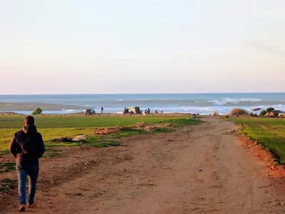 a woman walking down a dirt road near the ocean at Pool view apartment, beach access, nature & quiet in Mansouria