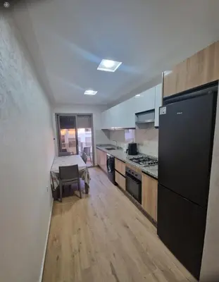 a kitchen with white cabinets and a black refrigerator at T3 confort Casablanca in Casablanca