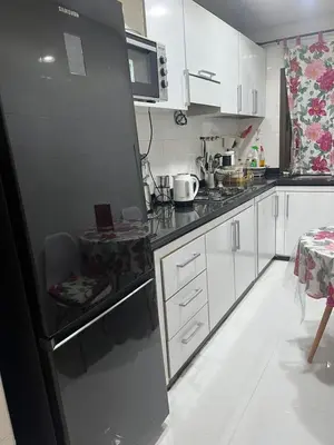 a kitchen with white cabinets and a black refrigerator at Perle de rabat 2 in Rabat