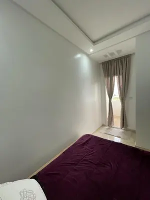a bedroom with a bed with purple sheets and a window at Apparemment Moderne à Temara in Temara