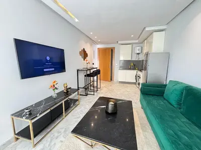 a living room with a green couch and a flat screen tv at Seabreeze home on the Corniche in Casablanca