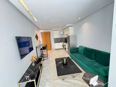 a living room with a green couch and a kitchen at Seabreeze home on the Corniche in Casablanca
