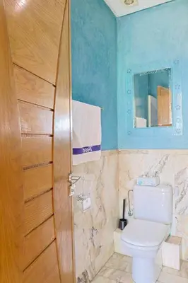 a bathroom with a toilet and a wooden door at La Coralline Pied dans l'eau, Vue apaisante in Casablanca