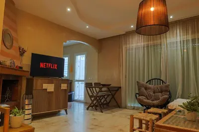 a living room with a television and a chair at La Coralline Pied dans l'eau, Vue apaisante in Casablanca