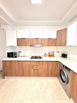 a kitchen with wooden cabinets and a washing machine at Bungalow à 1 minute de la plage in Rabat