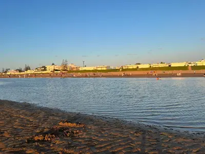 a beach with a body of water and people on the beach at Bungalow à 1 minute de la plage in Rabat