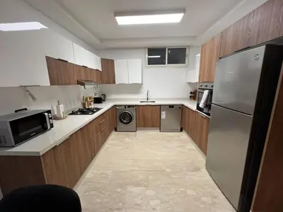 a kitchen with wooden cabinets and a stainless steel refrigerator at Bungalow à 1 minute de la plage in Rabat
