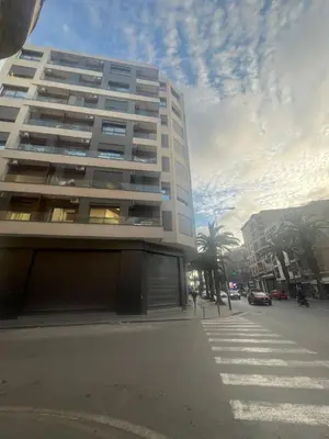 a tall white building on a street with palm trees at MR9-03 Nice corner in the heart of Casa in Casablanca