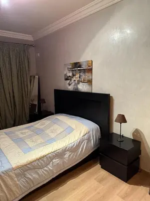 a bedroom with a bed and a table with a lamp at Comfortable apartment in Casablanca Assalam in Casablanca