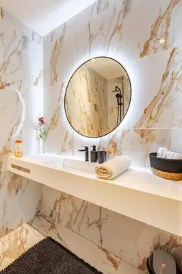 a bathroom with a mirror on a marble wall at Dynasty Estate Luxury Apartments in Palmiers, Casablanca in Maarif