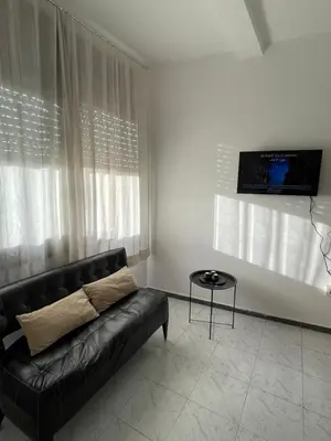 a living room with a black couch and a tv at Cozy getaway for a perfect stay in Rabat