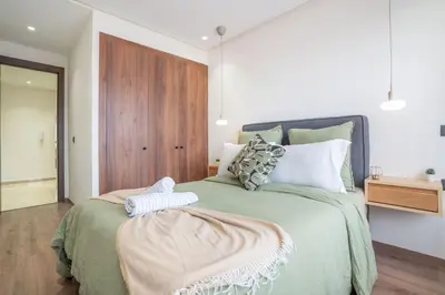 a bedroom with a green bed with a wooden door at Dynasty Estate Apartment Maarif with Parking Netflix Air Conditioning in Casablanca