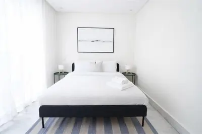 a white bedroom with a large bed and two tables at Appartement Lumineux à Racine, Bohème Chic in Casablanca