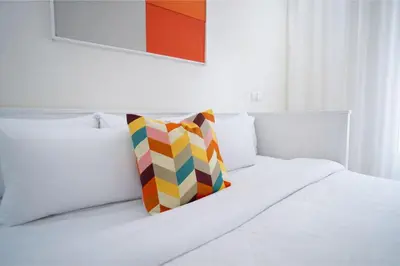 a colorful pillow sitting on top of a white bed at Appartement Lumineux à Racine, Bohème Chic in Casablanca