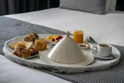 a tray with a plate of food on a bed at Boutique Hotel Gauthier Restaurant Terrasse in Casablanca