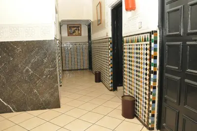 a hallway of a bathroom with a door and a tile floor at Hotel Boustane in Casablanca