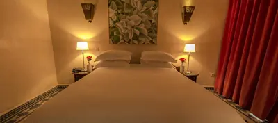 a bedroom with a large bed with two lamps at Soundouss Hotel in Rabat