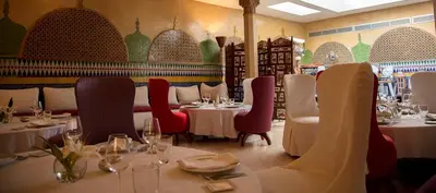 a restaurant with tables and chairs with wine glasses at Soundouss Hotel in Rabat